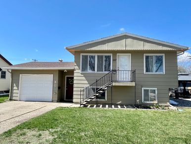A beige split-level house with a garage and front steps under a clear blue sky.