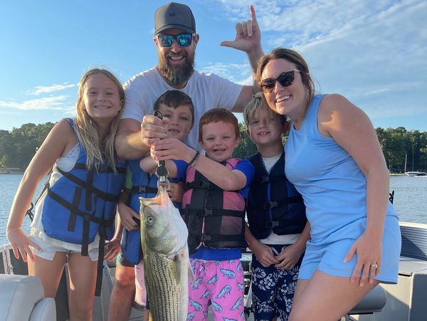Family on boat showing big fish catch.