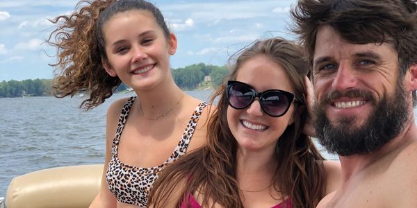 Three friends smiling on a boat on a sunny day.