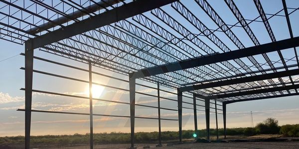 Steel framework of a building under construction at sunset.
