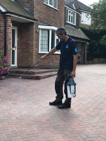 Applying a water based driveway sealant to enhance the aesthetics and help prevent weed growth.