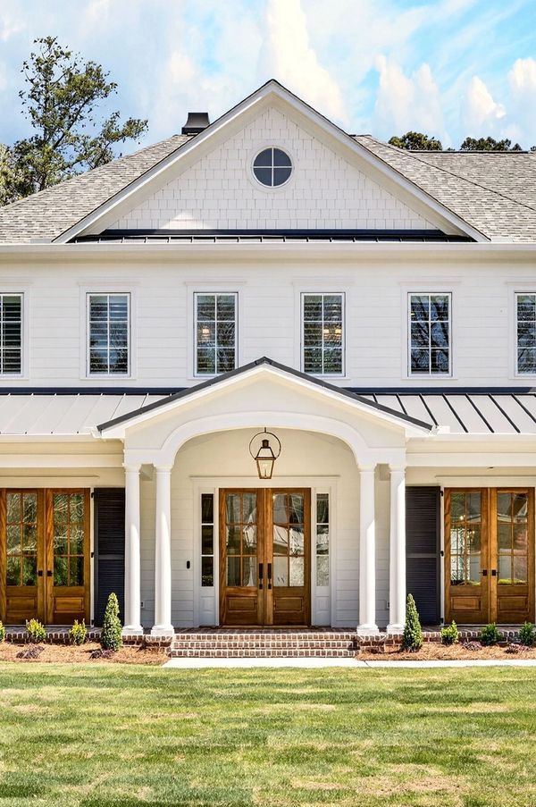 Elegant white two-story house with wooden doors and a manicured lawn.