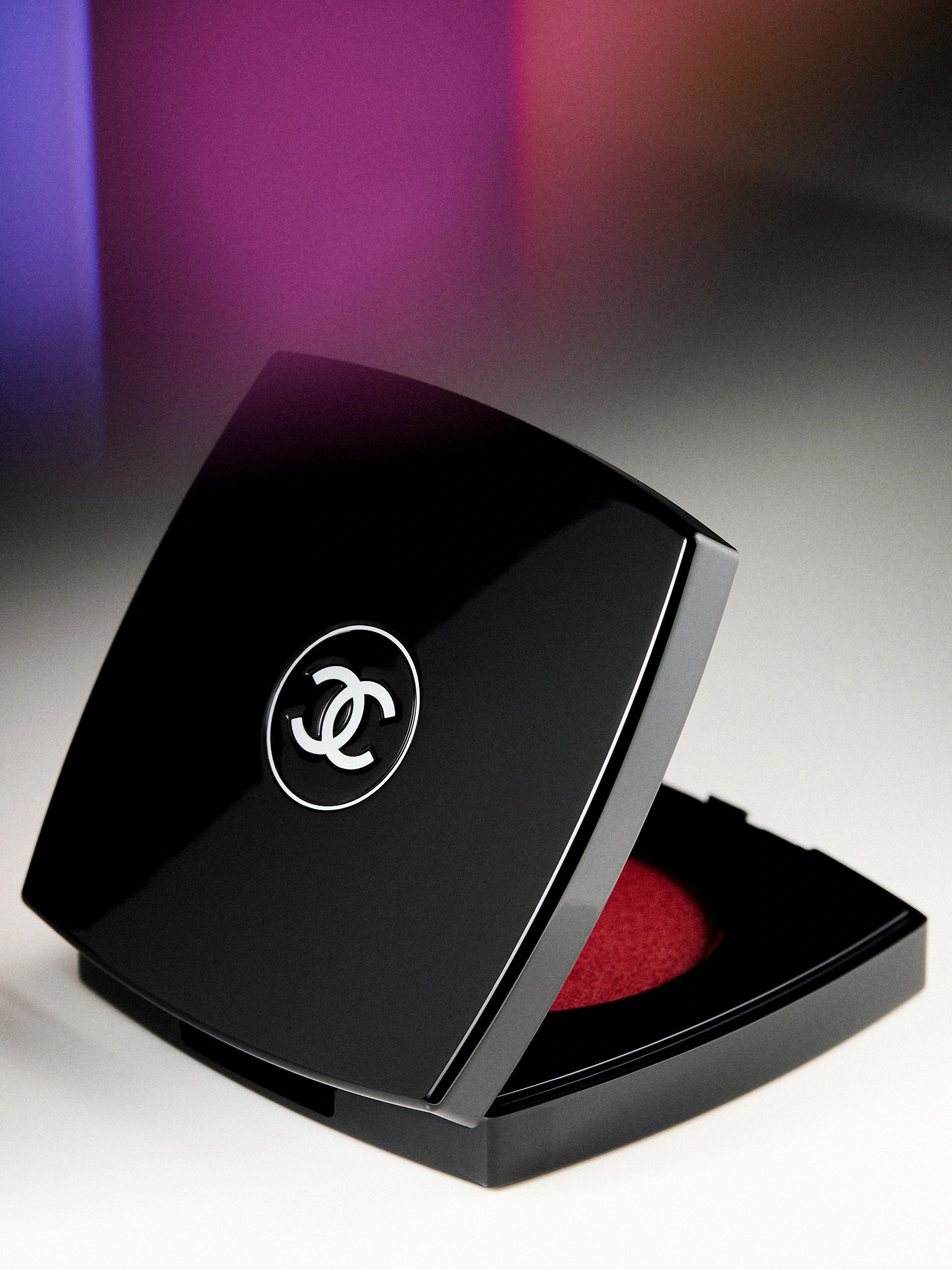 Close-up of a black Chanel makeup compact with red powder inside.