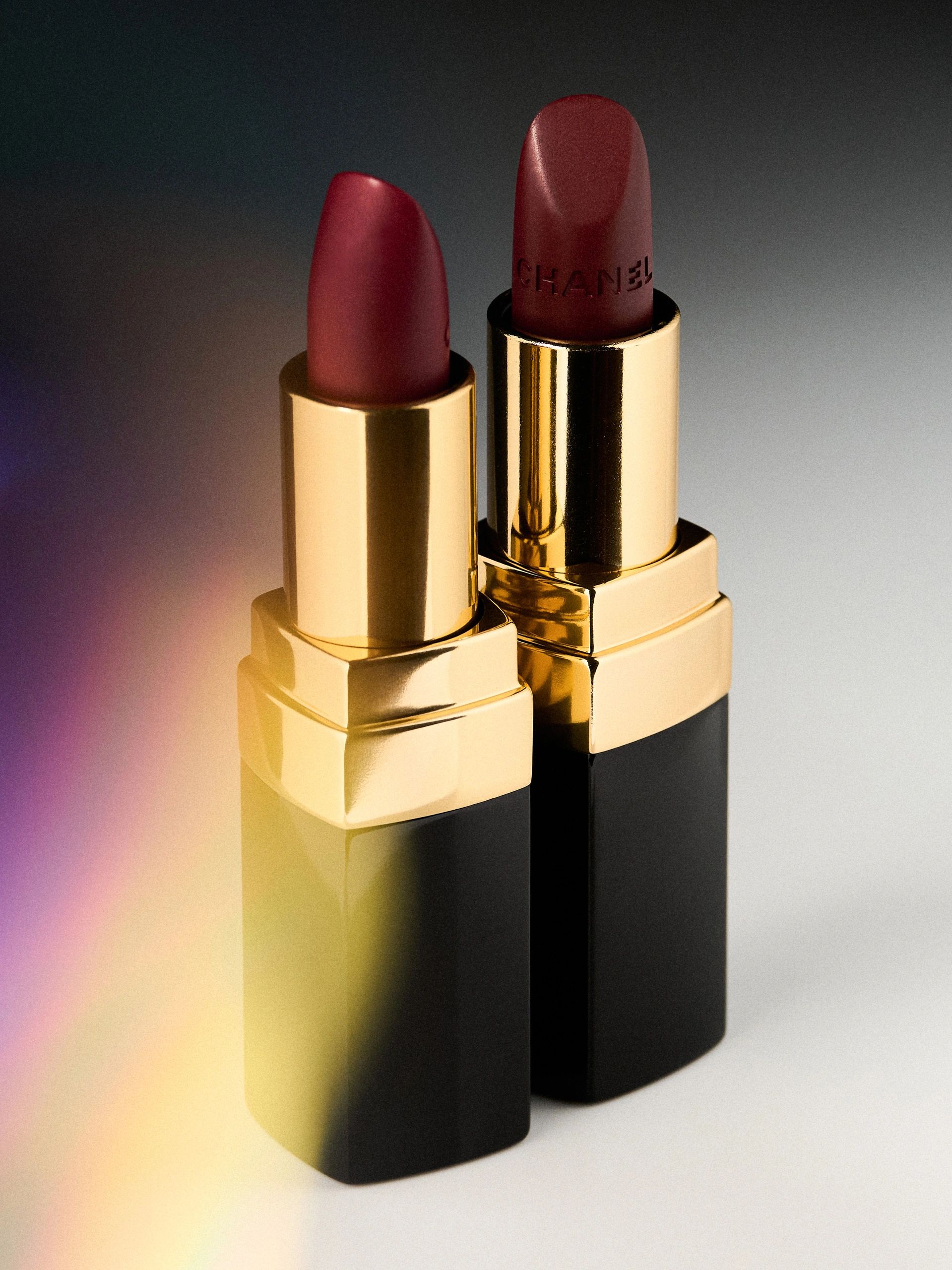 Two elegant dark red lipsticks in gold and black cases.