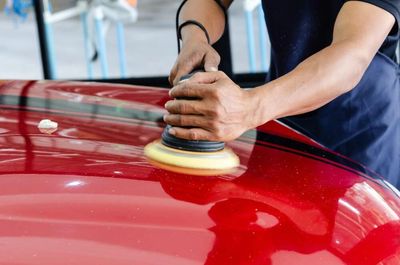 man applying car wax buffer on car hood