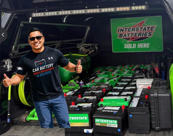 Man giving thumbs up in front of a truck loaded with Interstate car batteries.