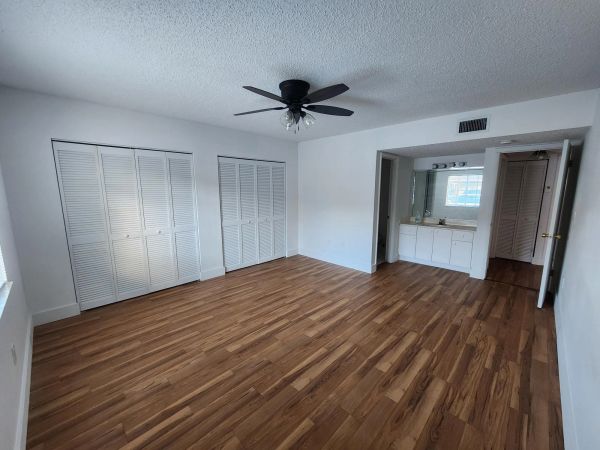 Empty room with wood flooring and ceiling fan.