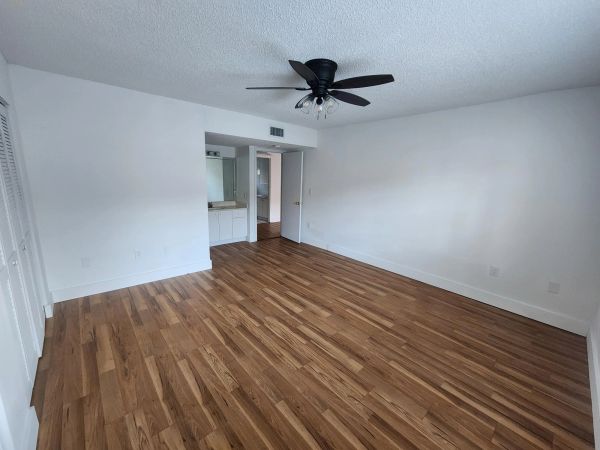 Empty bedroom with wooden floor and ceiling fan.