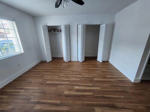 Empty room with two open closets and wooden flooring.