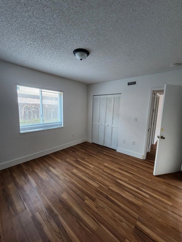 Empty room with wooden floor and window with blinds.