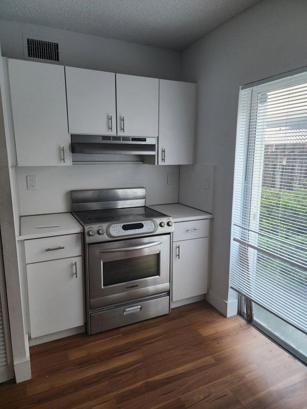 Modern kitchen with stainless steel stove and white cabinets.
