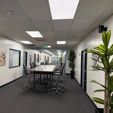 Modern office hallway with conference table and chairs.