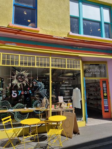Colorful storefront with yellow chairs and tables outside on a sunny day.