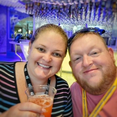 Smiling couple enjoying a drink together in a colorful, illuminated setting.