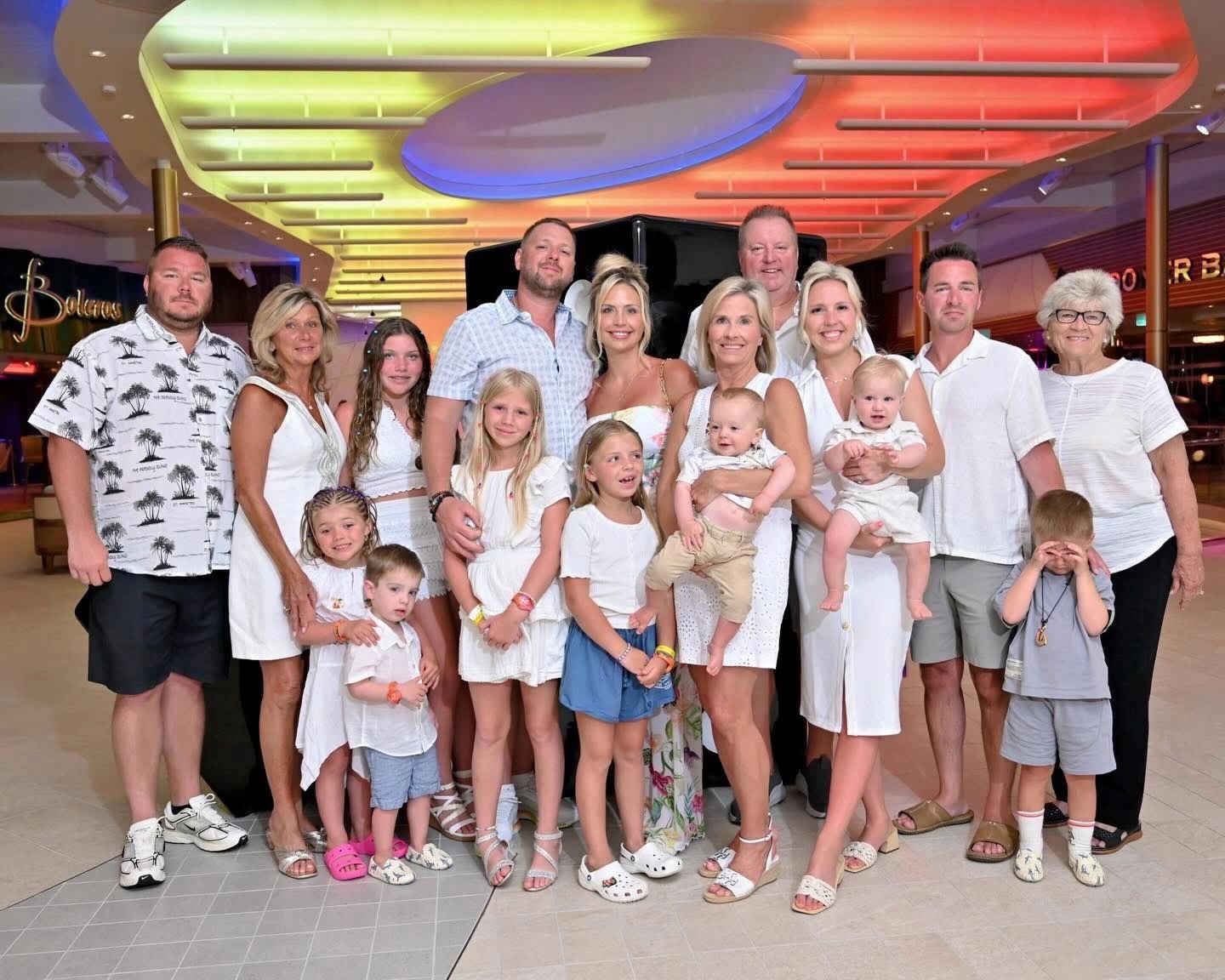 Large family group posing indoors under colorful ceiling lights.
