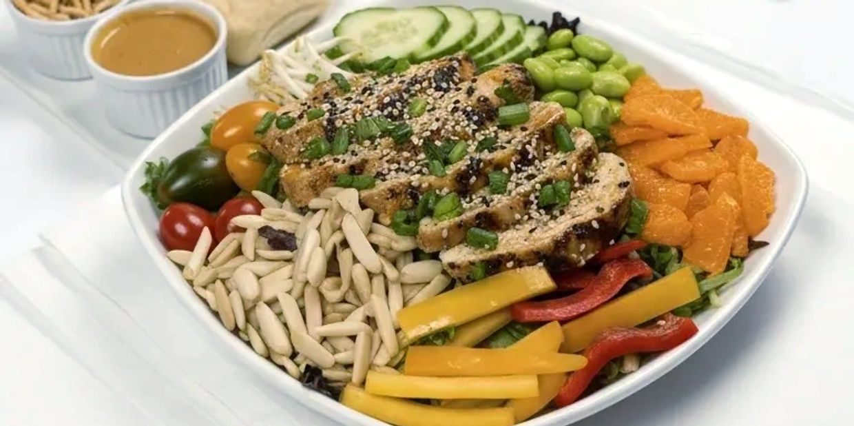 Colorful grilled chicken salad with fresh vegetables and seeds.