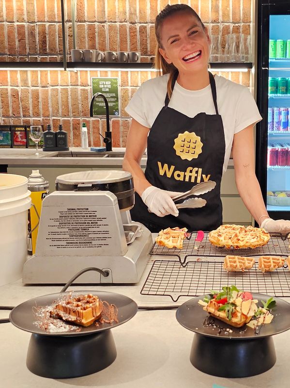 Smiling woman in a Waffly apron serving freshly made waffles.