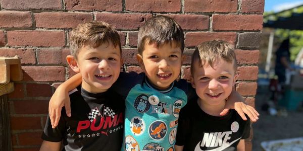 Three boys smiling with arms around each other.