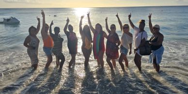 Group of friends posing joyfully at the beach during sunset.