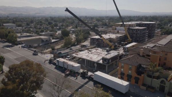 Construction site with cranes building multi-story structures in a suburban area.