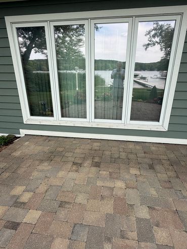 Reflection of a lake and trees in large glass windows of a house.