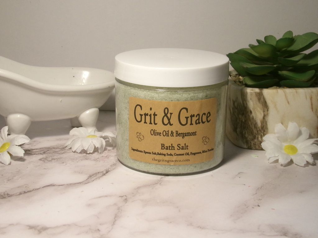 Jar of Grit &amp; Grace Olive Oil &amp; Bergamont Bath Salt on marble surface.