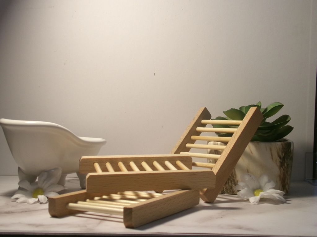 Wooden soap holders arranged with decorative flowers and a small bathtub-shaped container.