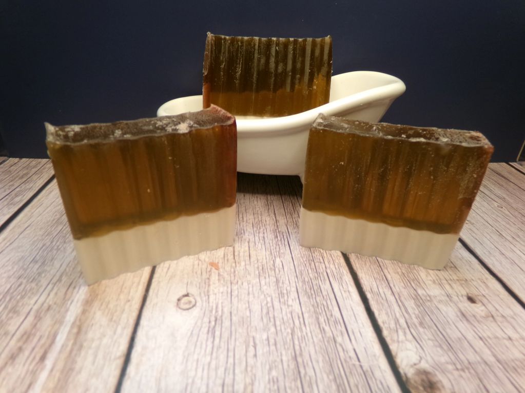 Three two-toned soap bars on a wooden surface with a white soap dish.