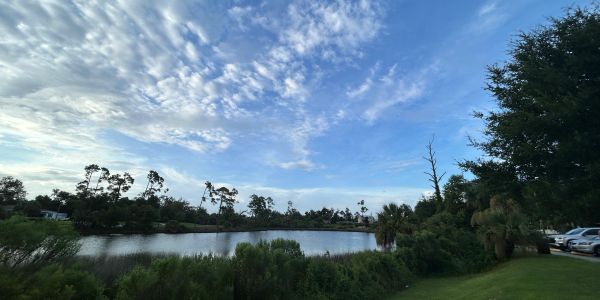 Calm lake under a partly cloudy blue sky.