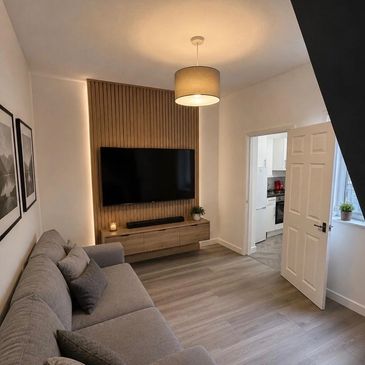 Modern living room with gray sofa, wooden TV console, and pendant light.