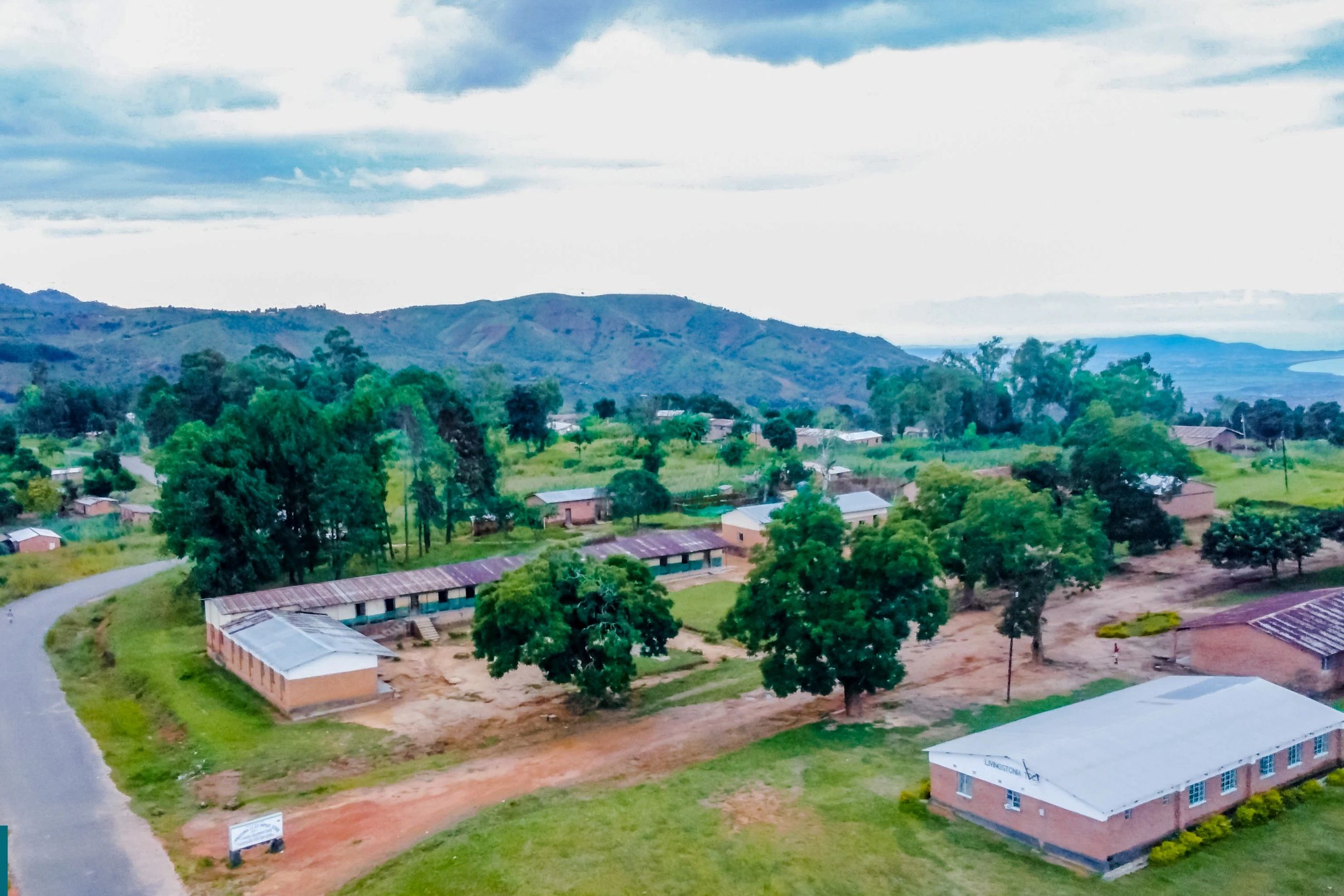 Rural school buildings surrounded by trees and hills.