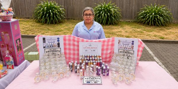 Woman selling fragrances at an outdoor market stall.