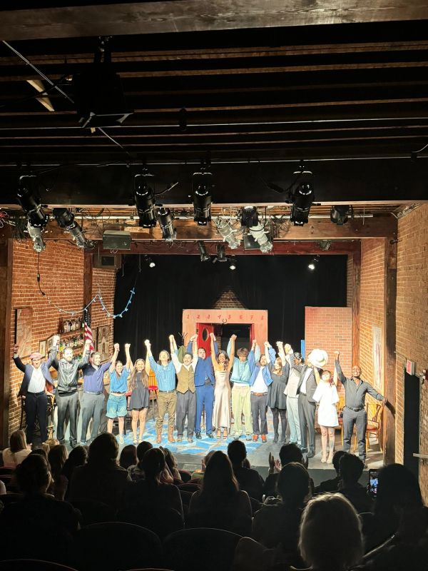 Cast taking a bow on stage with audience.
