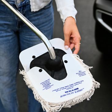 Person holding a unique auto mop with a metal handle and fringed edges.