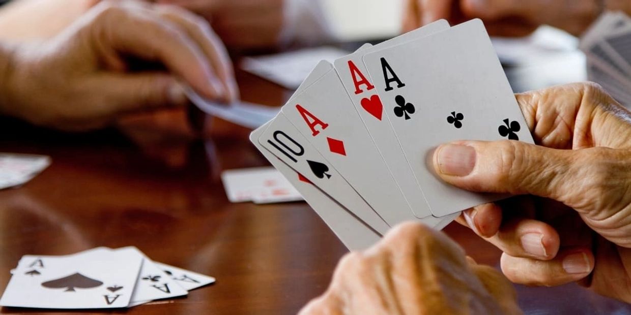 Hands holding playing cards during a card game.