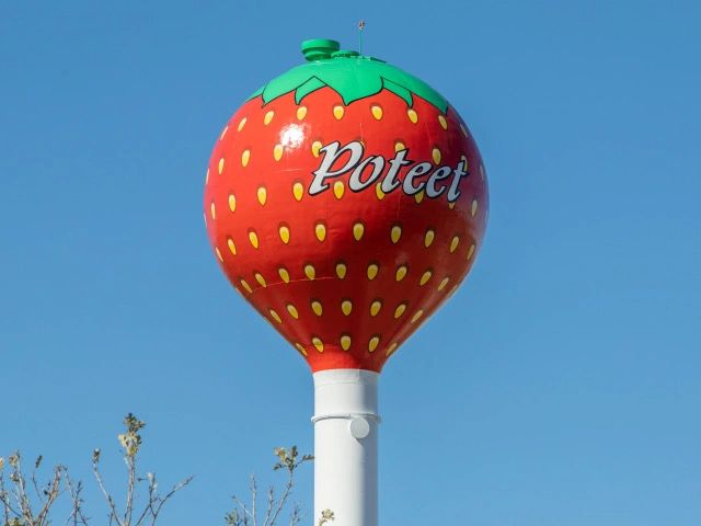 Water tower painted like a giant strawberry with 'Poteet' written on it.