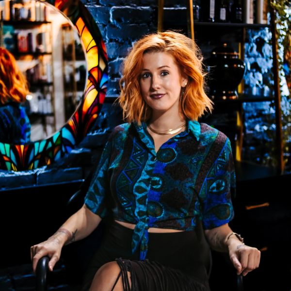 Young woman with red hair sitting in a stylish, dimly lit room.