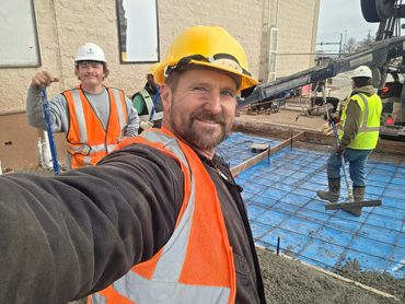 Construction workers in safety gear taking a selfie on site.