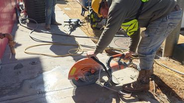 Construction worker cutting concrete with a power saw outdoors.