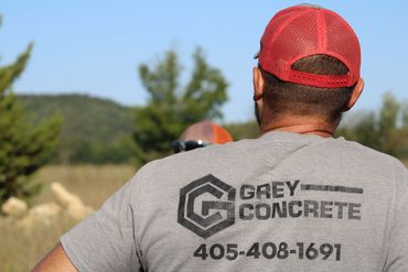 Man wearing a Grey Concrete t-shirt and red cap outdoors.