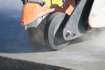 Close-up of a concrete saw cutting through a concrete slab.