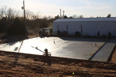 Workers finishing a freshly poured concrete slab on a sunny day.
