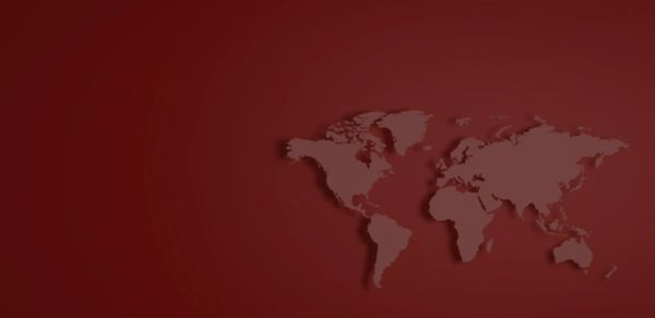 Minimalist world map silhouette on a deep red background.