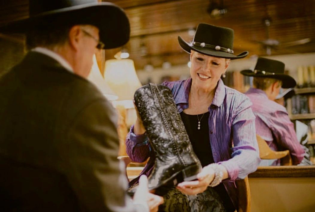 Woman showing a cowboy boot to a man in a store.