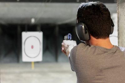 Man practicing shooting at a range wearing ear protection.