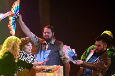 Four people performing with colorful fans on stage.
