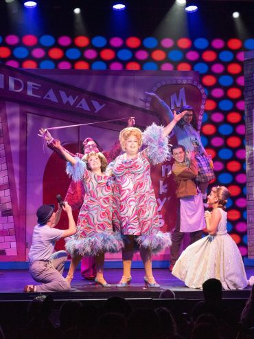 Two women in matching colorful dresses performing on stage.