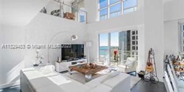 Modern white living room with high ceilings and ocean view.