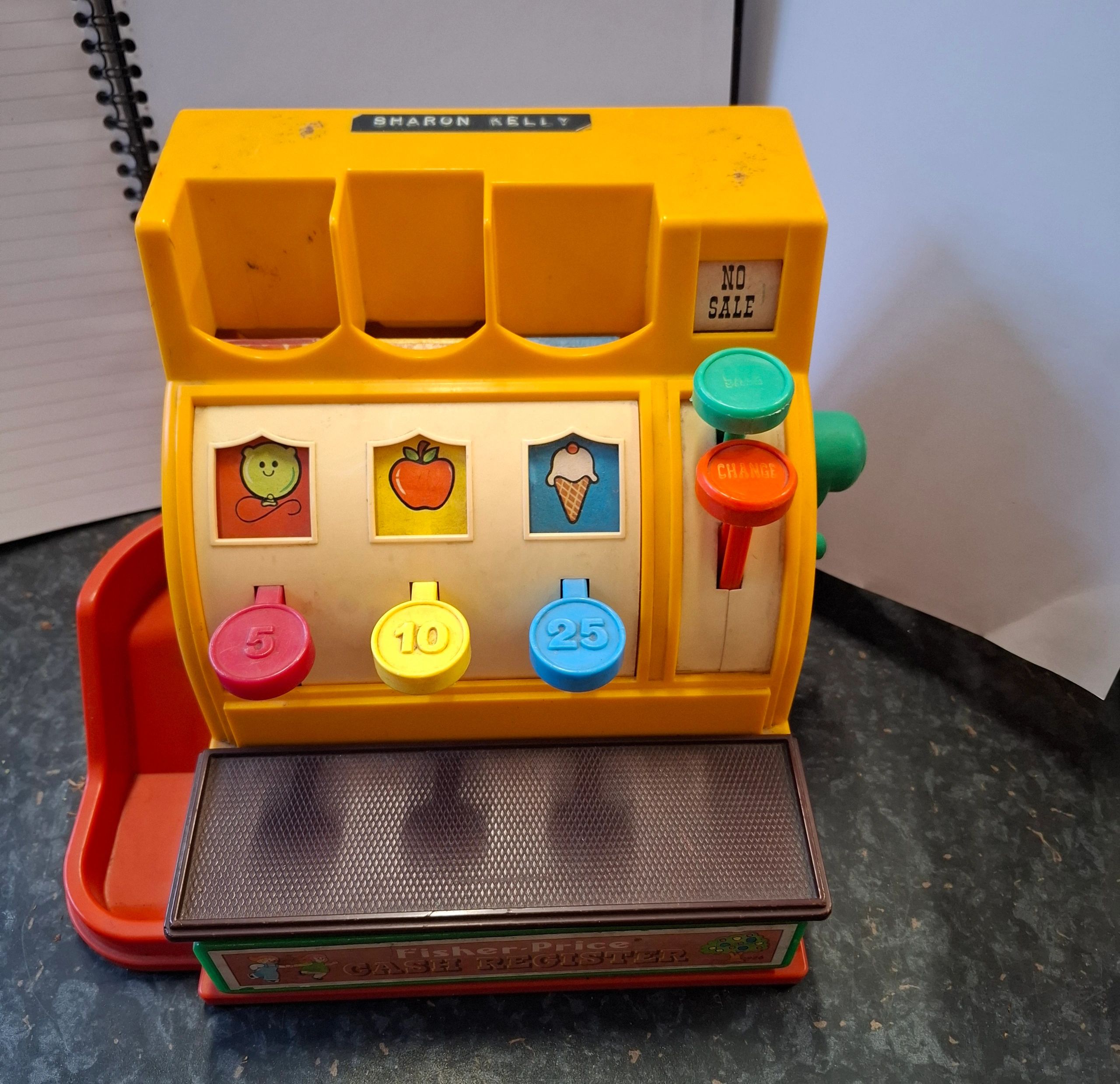 Vintage Fisher-Price toy cash register with colorful buttons and fruit icons.