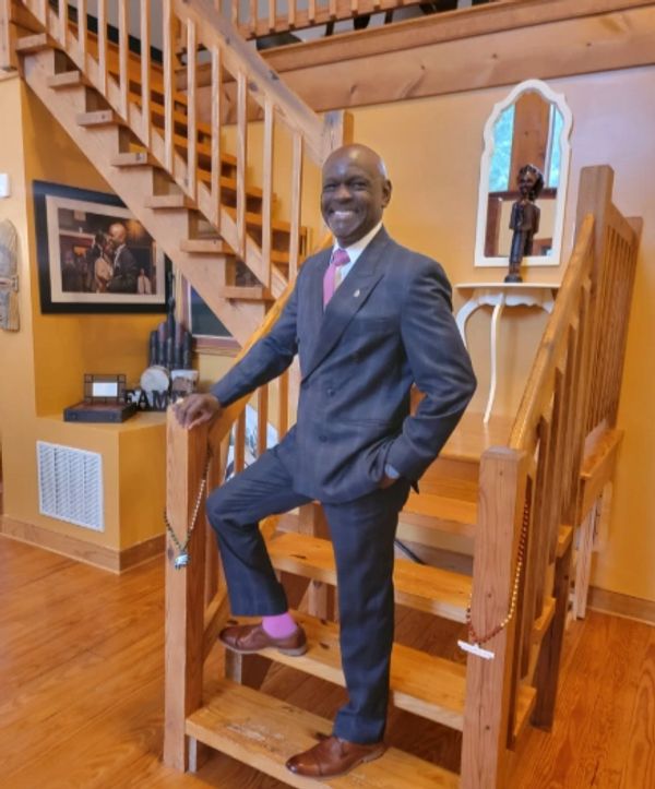 Man in suit standing on wooden stairs.